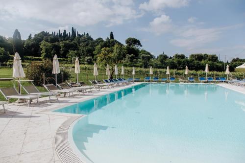 a large swimming pool with chairs and umbrellas at Agriturismo Le Caldane in Colà di Lazise
