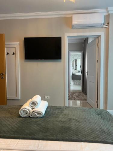a bedroom with a bed with towels and a flat screen tv at Vila DLK in Mamaia Sat/Năvodari