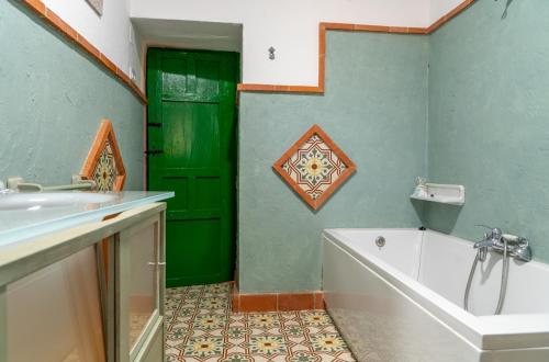 a bathroom with a green door and a bath tub at Cortijo el Vicario in Ronda