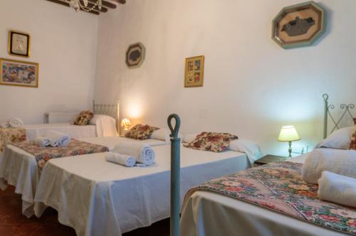 a room with three beds with white sheets at Cortijo el Vicario in Ronda