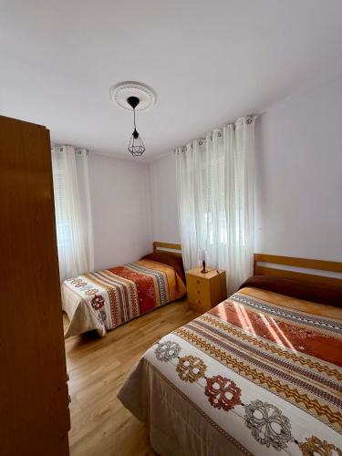 two beds in a room with white walls and wooden floors at Pensión O Regato in Redondela