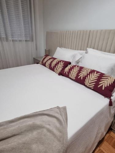 a white bed with two pillows on top of it at Apartamento Brisa in Viana do Castelo