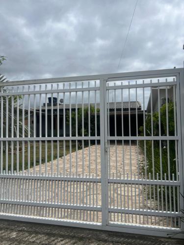 a white fence with a gate in front of a building at Residência Rosalaura in Balneário Gaivotas