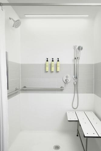 a bathroom with a shower with three bottles on a shelf at Element by Marriott Opelika Auburn in Opelika