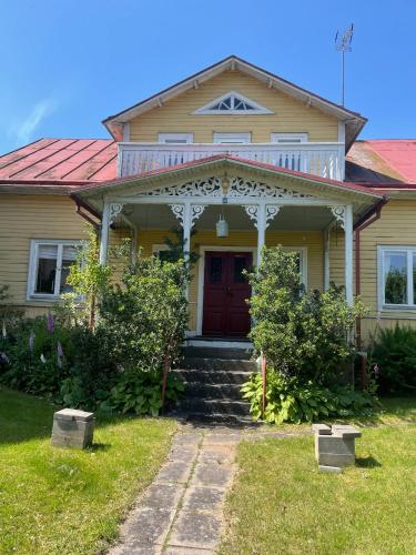 a yellow house with a red door and a yard at Ankis i Virserum in Virserum
