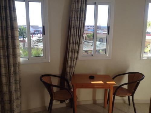 - une table et deux chaises dans une chambre avec deux fenêtres dans l'établissement Motel Paris Dakar, à Selouane