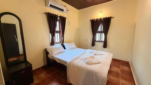 a small bedroom with a bed and a mirror at Coastal Hideout Family Cottages Malpe Beach in Malpe
