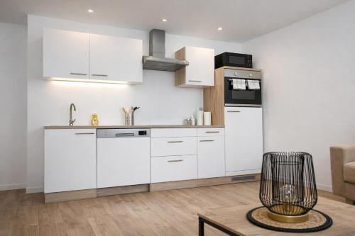 a kitchen with white cabinets and a table at Joli T2 proche parc expo in Mulhouse