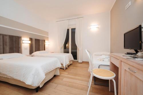 a hotel room with two beds and a flat screen tv at Hotel Di Nardo in Petacciato
