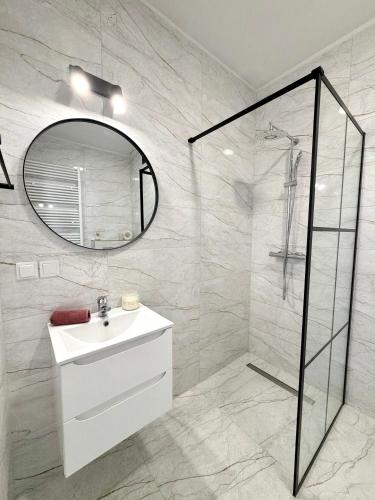 a white bathroom with a sink and a mirror at Apartament Stare Miasto 2 in Elblag