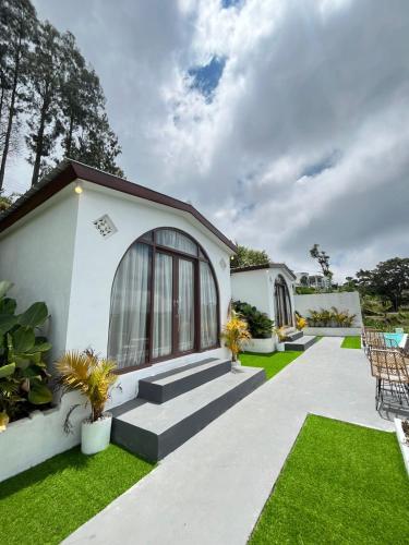 a white house with a patio and grass at jungle camping in Baturaja