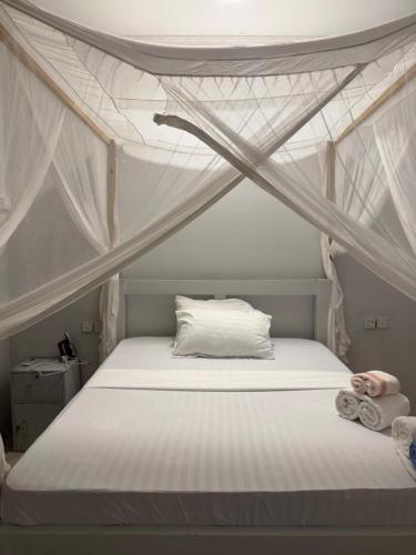 ein Schlafzimmer mit einem Himmelbett mit weißen Laken in der Unterkunft Dindini in Kilindoni