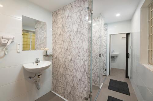 a white bathroom with a sink and a shower at Hanoi Oldtown Nomad Hostel & Pub in Hanoi