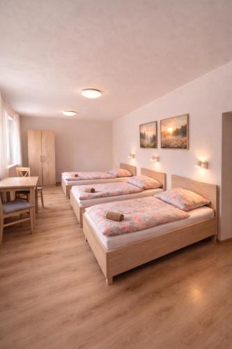 a row of beds in a room with a table at Pohoda Stay in Revúca
