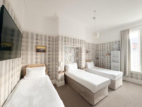 a bedroom with two beds and a flat screen tv at The Raincliffe Hotel in Scarborough