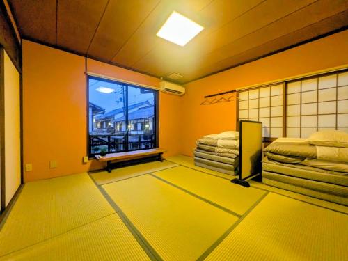 a room with yellow walls and a large window at 長浜ゲストハウスミカタ Guest House Mikata in Nagahama