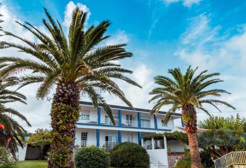 a building with palm trees in front of it at Porto Martins Bay Apartments (AL) in Porto Martins