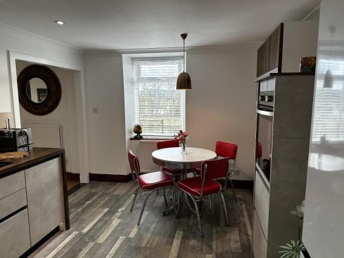 a kitchen and dining room with a table and red chairs at Sealladh Sona in Inverness