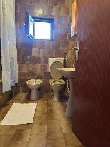 a bathroom with a toilet and sink and a window at Apartmani VV in Cetinje
