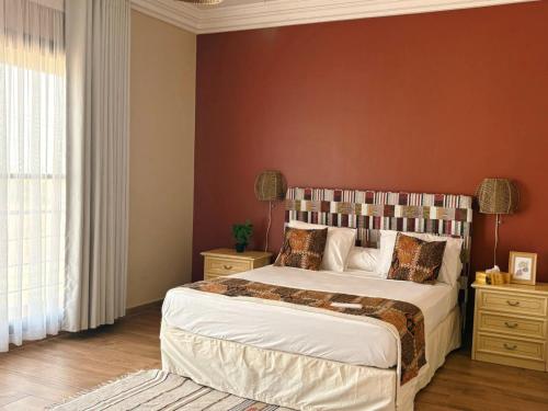 a bedroom with a large bed with a red wall at Villa Le Charme de Somone Piscine privée confort & proximité plage in Somone