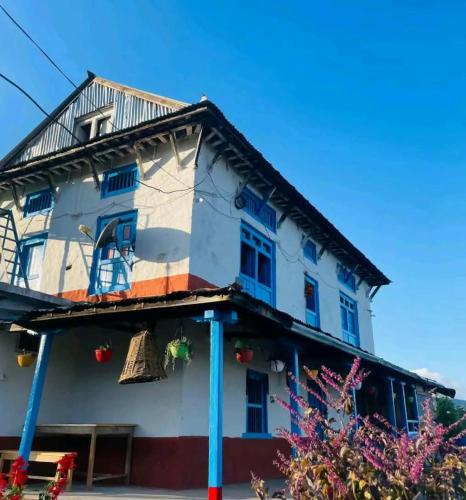 a house with a thatched roof and blue windows at Naranthan daura chulo homestay in Panaoti