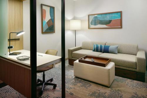 a living room with a couch and a desk in a hotel room at SpringHill Suites by Marriott Locust Grove in Locust Grove