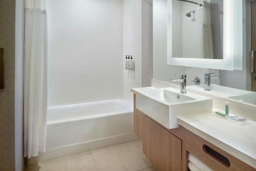 a bathroom with a sink and a shower and a tub at SpringHill Suites by Marriott Locust Grove in Locust Grove