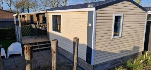 a shed with a deck with a table and chairs at Chalet B2 900 m vom Strand in Koudekerke