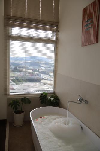 a bath tub in a bathroom with a window at 1909 Home Dalat - Open 24h in Ấp Kim Thạch