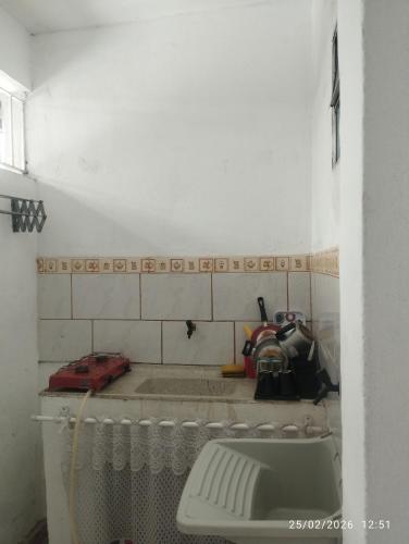 a bathroom with a sink and a white tiled wall at Quitinete 5 Itaguaí in Itaguaí