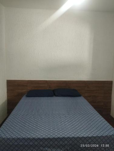 a bedroom with a bed with blue sheets and a light at Quitinete 5 Itaguaí in Itaguaí