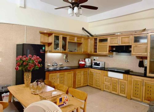 a kitchen with wooden cabinets and a table with flowers at Ribi Home in Hà Ðông