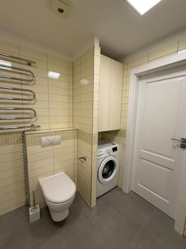 a bathroom with a toilet and a washing machine at Bird's eye Apartment with sea view 18th floor in Klaipėda