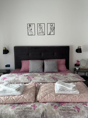 a bedroom with a large bed with pink and grey pillows at Apartman Harmonija in Bajina Bašta