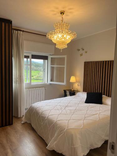 a bedroom with a large white bed and a chandelier at Balcón del cubo in Covaleda