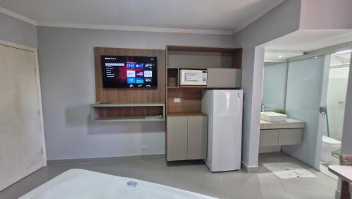 a kitchen with a refrigerator and a tv on the wall at Araras Apart Service in Caldas Novas