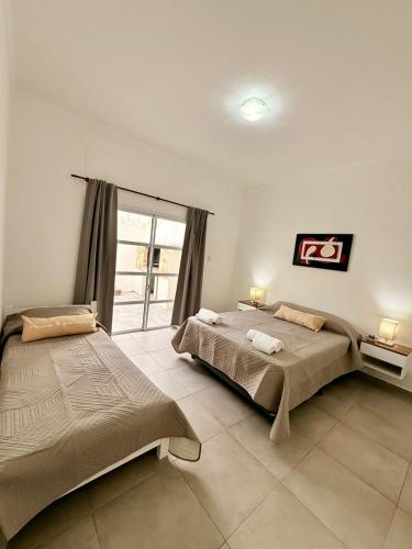 a bedroom with two beds and a large window at Pausa Bragado in Bragado
