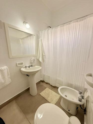 a white bathroom with a toilet and a sink at Pausa Bragado in Bragado