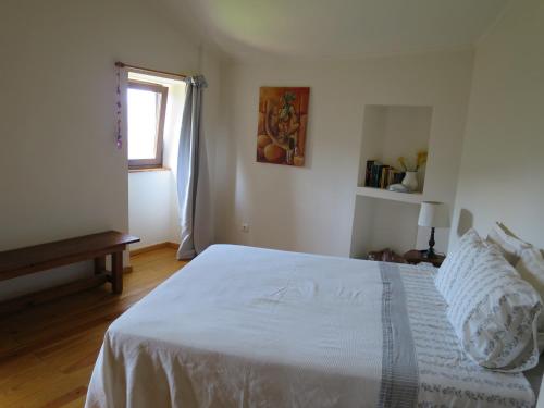a white bedroom with a bed and a window at Casa das Oliveiras in Colmeal