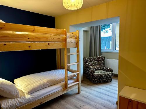 a bedroom with a bunk bed and a chair at Berghaus Wanderlust in Mallnitz