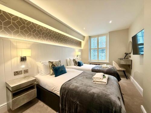 a hotel room with two beds and a television at Modern 3 Bedroom Apartment, West End in Edinburgh