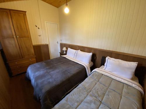 a bedroom with two beds and a closet with a door at Campos do Jordão à moda antiga in Campos do Jordão