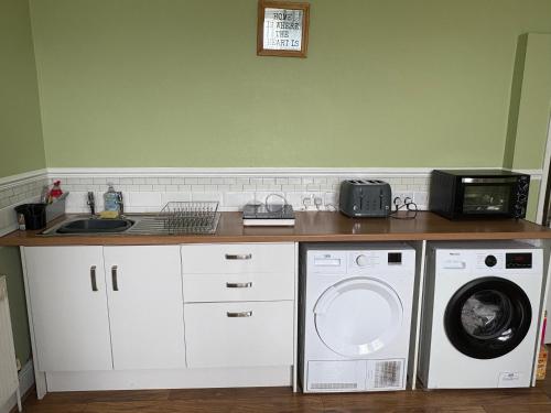 a kitchen with a washing machine and a microwave at Runcorn Jubilee Guest House in Runcorn