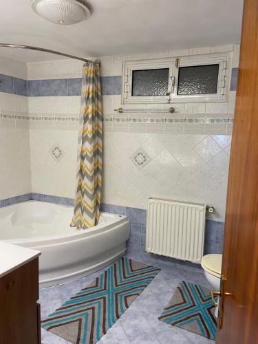 a bathroom with a tub and a shower curtain at BLUE PANORAMA CRYSTAL with Amazing Sea View in Makri