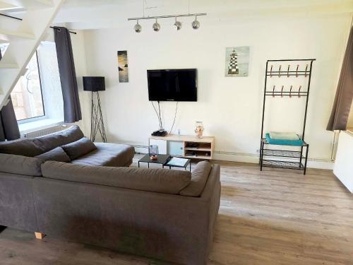a living room with a couch and a flat screen tv at Gite Les Sables Blancs in Plobannalec-Lesconil