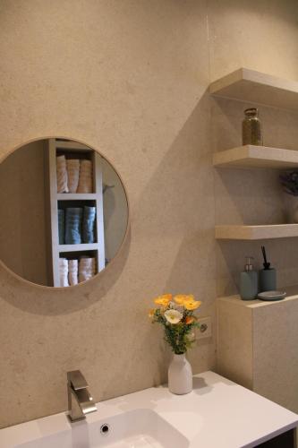 a bathroom sink with a mirror and a vase with flowers at Ons Heerens Boompje in Poperinge