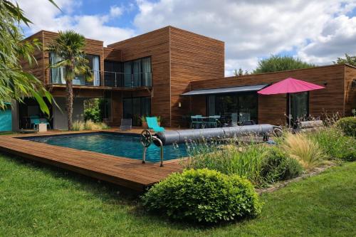 a home with a swimming pool and a house at Cap Ferret Villa Océane in Lège-Cap-Ferret