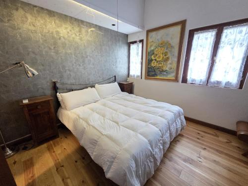 a bedroom with a large bed with white sheets at La Volpe e L'Iris in Campiano, Province of Verona