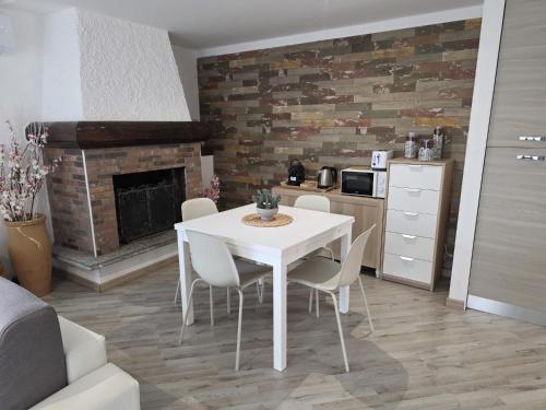 a white table and chairs in a kitchen with a fireplace at Cannella Comfort Apartment in Bellagio