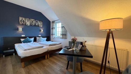 a bedroom with a bed and a table with a lamp at Hotel Wuelfers Gasthaus in Groß Ippener